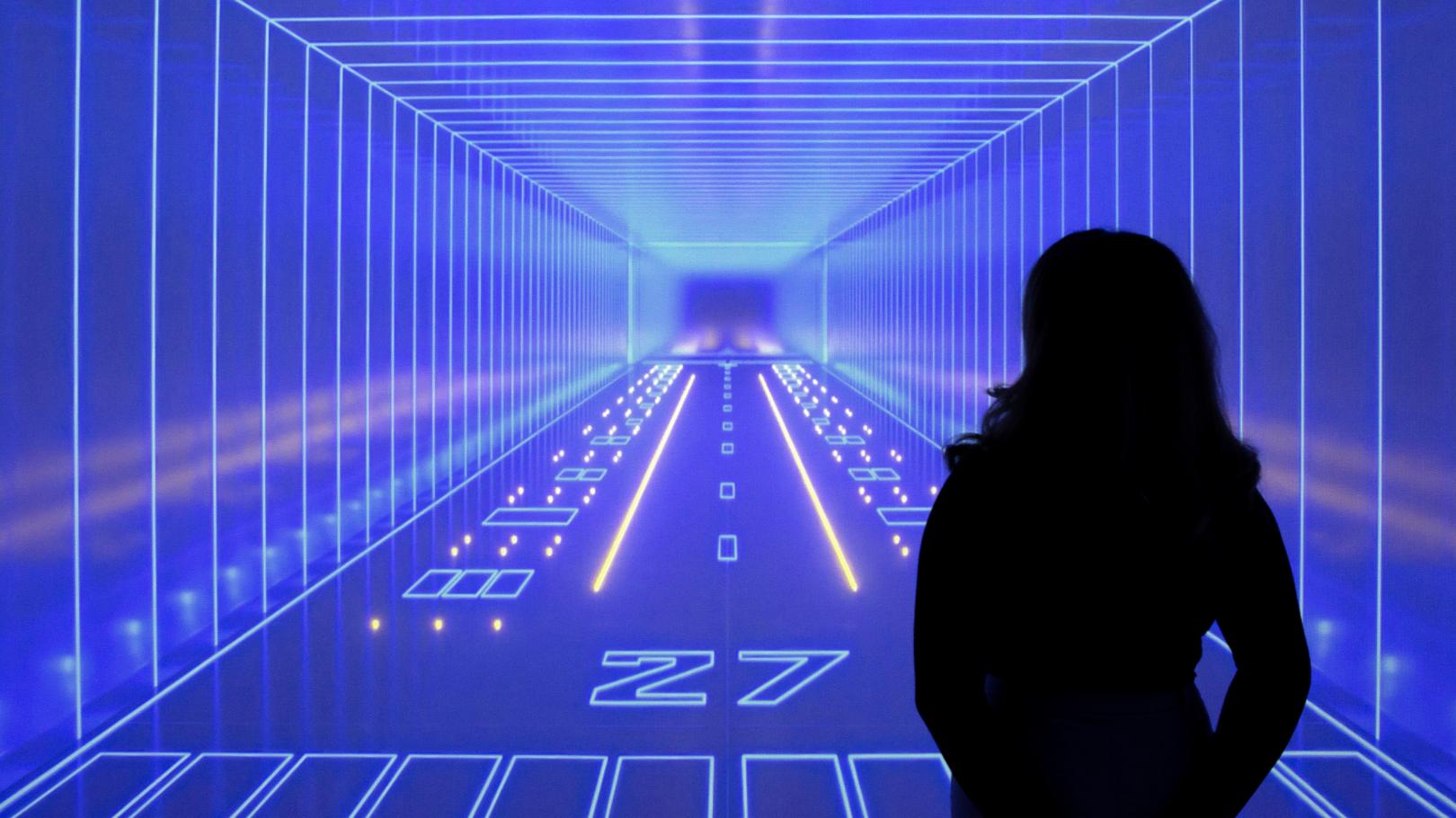 the silohuette of a woman in front of a bright blue image depicting a fantastical neon runway inside an endless tunnel
