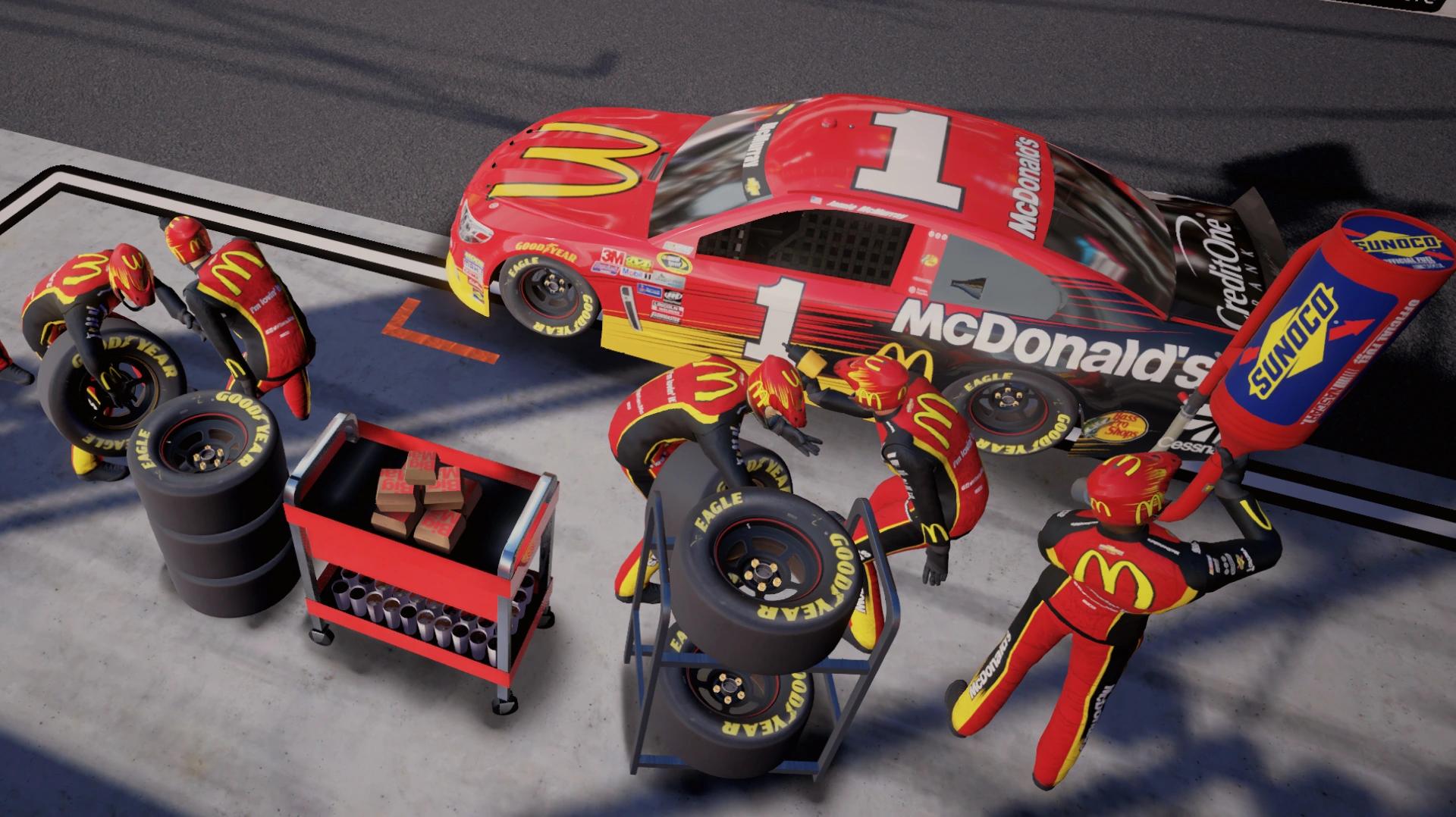 five members of the pit crew approach the McDonalds NASCAR car with new tires and gas
